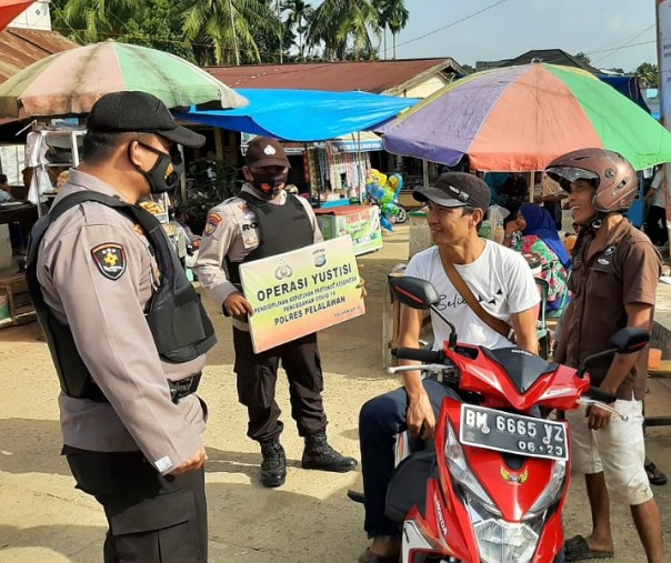 Personel Polsek Ukui menegur pengendara motor yang tak mengenakan masker saat Operasi Yustisi di pasar tradisional, Selasa (19/1/2021). Foto: Istimewa. 