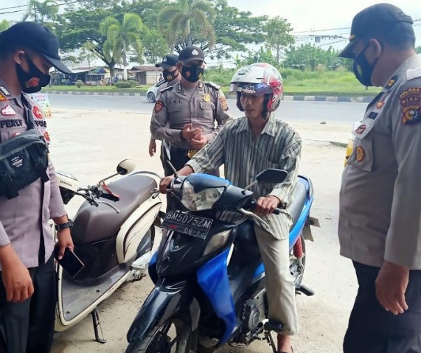 Personel Polsek Pangkalan Kerinci menegur pengendara motor yang tak mengenakan masker saat Operasi Yustisi di Jalan Lintas Timur Pelalawan, Rabu (20/1/2021). Foto: Istimewa. 