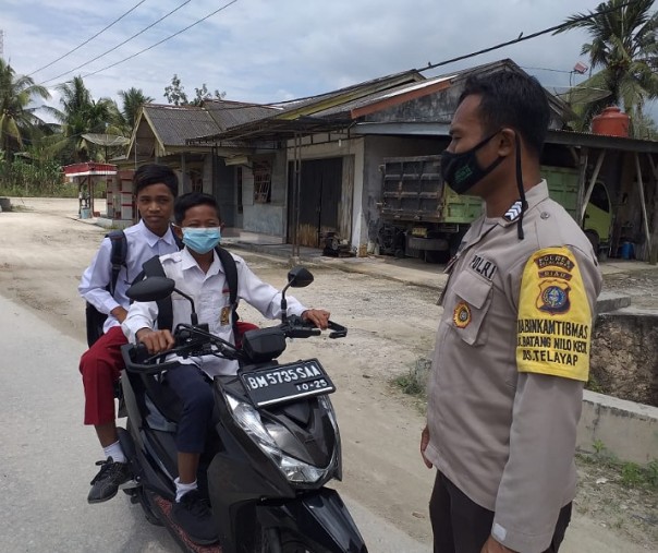 Personel Polsubsektor Pelalawan saat menemukan seorang murid SD tak pakai masker saat berkendara di Desa Lalang Kabung, Selasa (26/1/2021). Foto: Istimewa. 