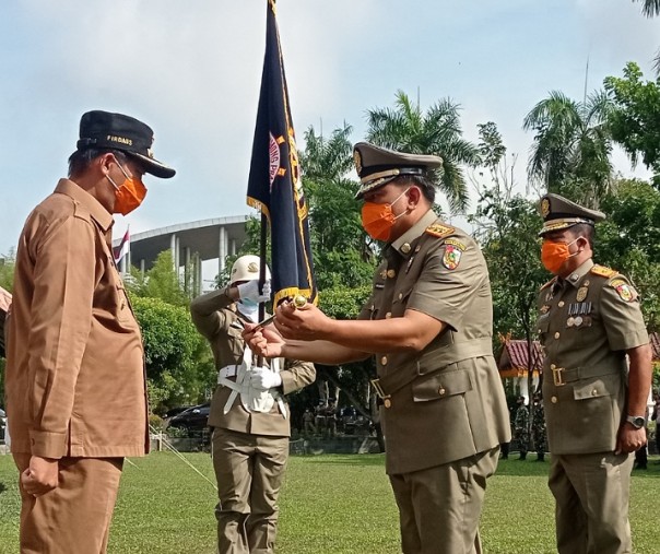 Kepala Satpol PP Pekanbaru Iwan Simatupang menerima tongkat komando dari Wali Kota Firdaus didampingi pejabat sebelumnya Burhan Gurning dalam upacara serah terima jabatan di halaman Mal Pelayanan Publik, Selasa (9/2/2021). Foto: Surya/Riau1.