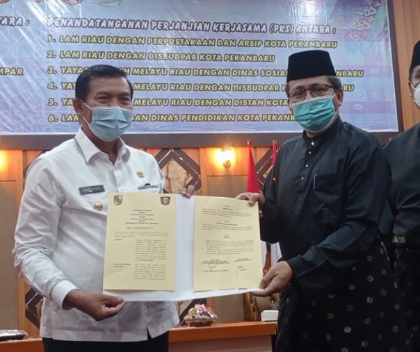 Wali Kota Pekanbaru Firdaus bersama Ketua DPH LAM Riau Datuk Seri Syahril Abu Bakar melibatkan MoU yang telah diteken, Selasa (23/2/2021). Foto: Surya/Riau1.