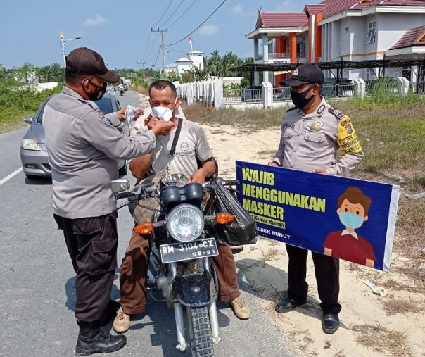 Polsek Bunut bersama dengan Puskesmas Bunut dan Satpol PP Kabupaten Pelalawan melaksanakan Operasi Yustisi dan membagikan masker ke pengendara di Jalan Lintas Bono, Desa Petani, Selasa (23/2/2021). Foto: Istimewa. 