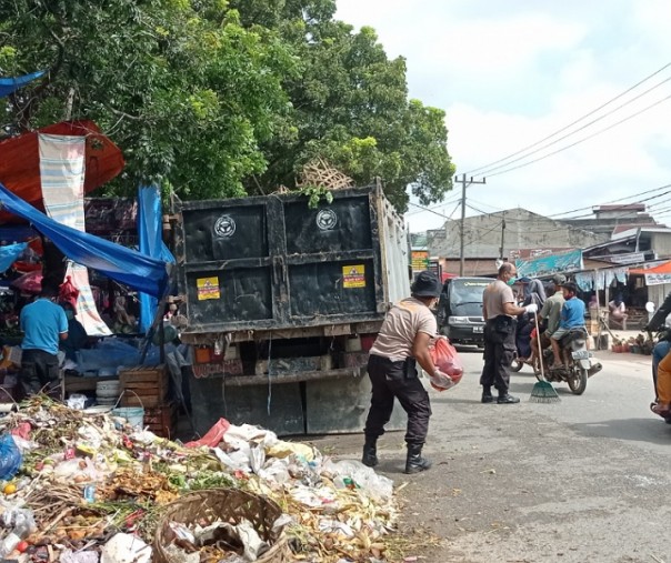 Petugas kepolisian ikut membantu membersihkan tumpukan sampah di depan Pasar Tangor, Kecamatan Kulim, beberapa pekan lalu. Foto: Surya/Riau1.