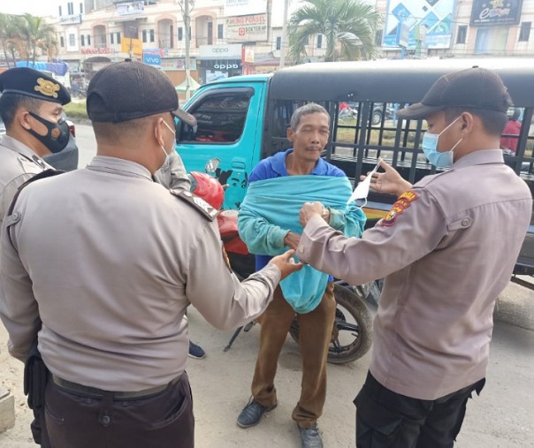 Personel Polsek Pangkalan Kerinci membagikan masker kepada warga, Selasa (2/3/2021). Foto: Istimewa. 