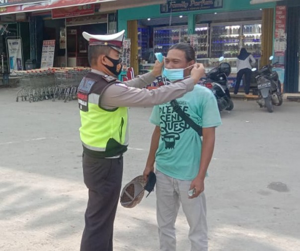 Personel Polsek Pangkalan Kerinci membagikan masker ke warga di Mandiri Swalayan, Sabtu (6/2/2021). Foto: Istimewa. 