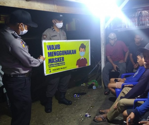 Polsek Bunut saat sosialisasi prokes ke warga yang duduk di warung, Minggu (7/3/2021) malam. Foto: Istimewa. 