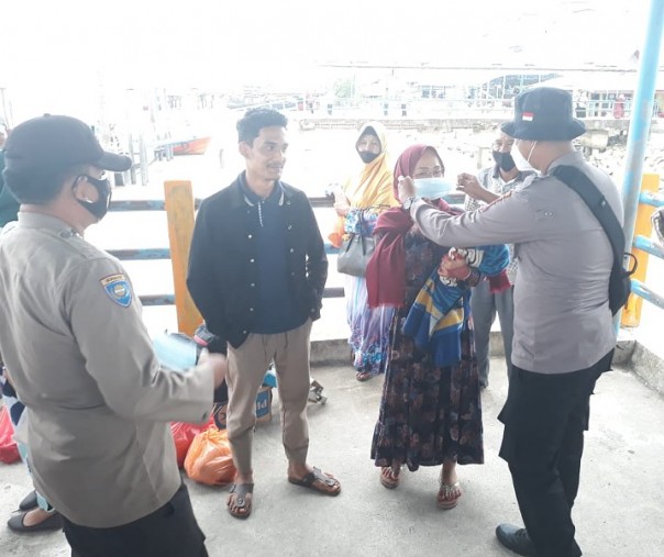Polsek Kuala Kampar membagikan masker ke penumpang kapal di Pelabuhan Kelurahan Teluk Dalam, Senin (8/3/2021). Foto: Istimewa. 