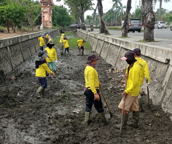 Pasukan kuning Dinas PUPR Pekanbaru saat membersihkan drainase di Jalan Jenderal Sudirman. Foto: Surya/Riau1.