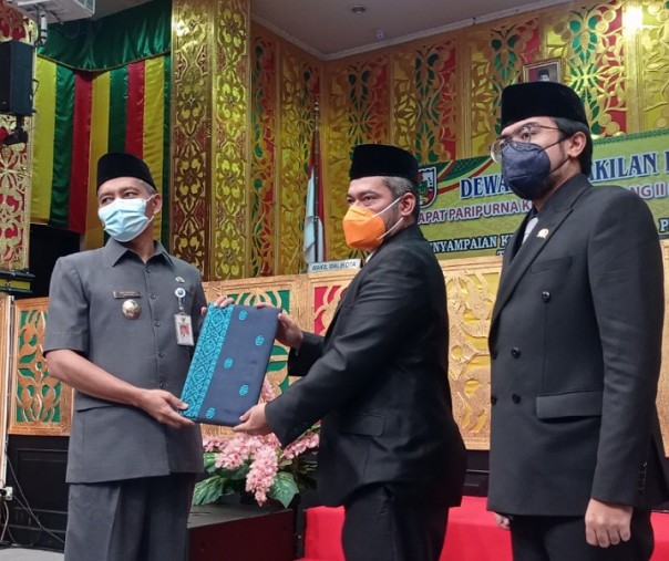 Ketua DPRD Pekanbaru Hamdani (tengah) menyerahkan keputusan LKPJ 2020 ke Wakil Wali Kota Ayat Cahyadi (kiri), Selasa (27/4/2021). Foto: Surya/Riau1.