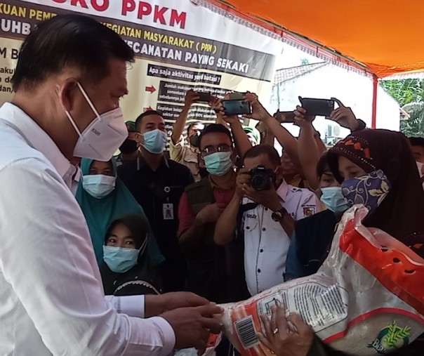 Wali Kota Pekanbaru Firdaus menyerahkan bansos beras kepada warga di halaman Kantor Kelurahan Labuhbaru Barat, Kecamatan Payung Sekaki, Rabu (21/7/2021). Foto: Surya/Riau1.