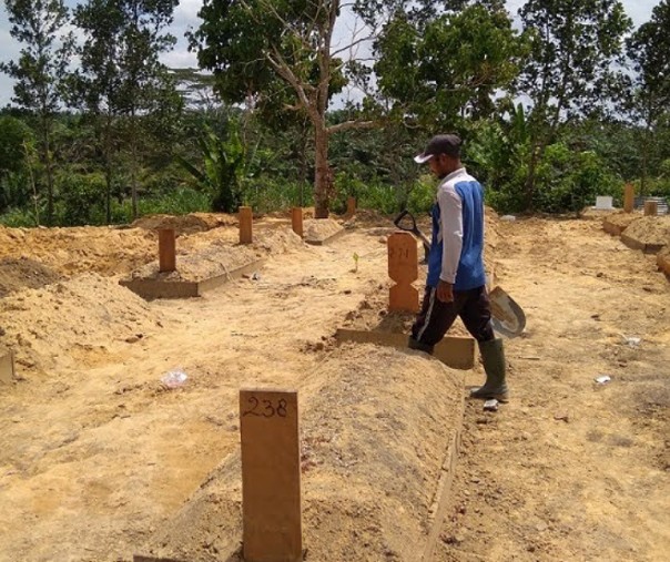 Seorang penggali kubur berjalan di antara makam jenazah Covid-19 di TPU Tengku Mahmud. Foto: Surya/Riau1.