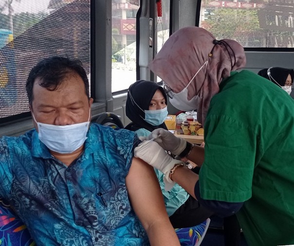 Seorang warga saat divaksin di dalam bus vaksinasi keliling. Foto: Surya/Riau1.