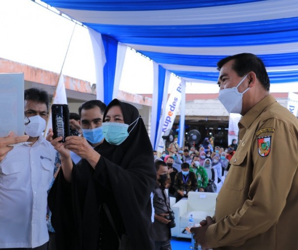 Wali Kota Pekanbaru Firdaus menyaksikan warga memindai kode QRIS melalu smartphone di Pasar Limapuluh, Senin (15/11/2021). Foto: Istimewa. 