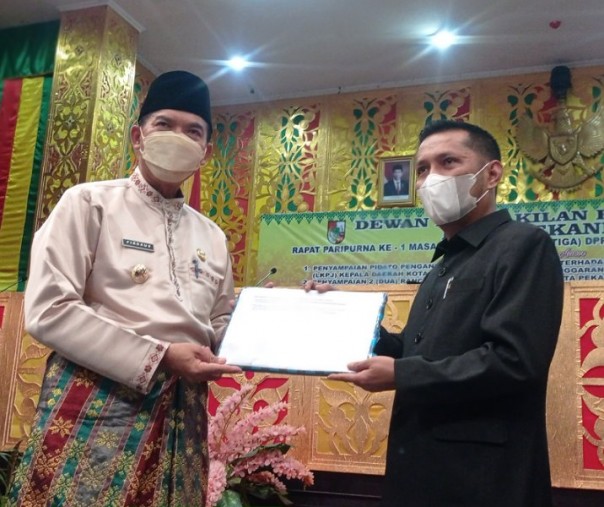 Wali Kota Pekanbaru Firdaus menyerahkan dokumen LKPj kepada pimpinan sidang paripurna DPRD Tengku Azwendi, Selasa (17/5/2022). Foto: Surya/Riau1.