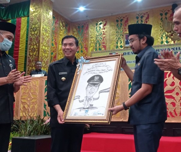 Wali Kota Pekanbaru Firdaus mendapat cendera mata berupa karikatur dari pimpinan DPRD sebagai tanda perpisahan, Kamis (19/5/2022). Foto: Surya/Riau1.