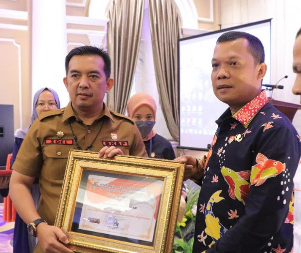 Kepala Badan Kesbangpol Pekanbaru Zulfahmi Adrian menyerahkan piagam penghargaan kepada Pj Wali Kota Muflihun di Hotel Royal Asnof, Kamis (7/7/2022). Foto: Istimewa. 