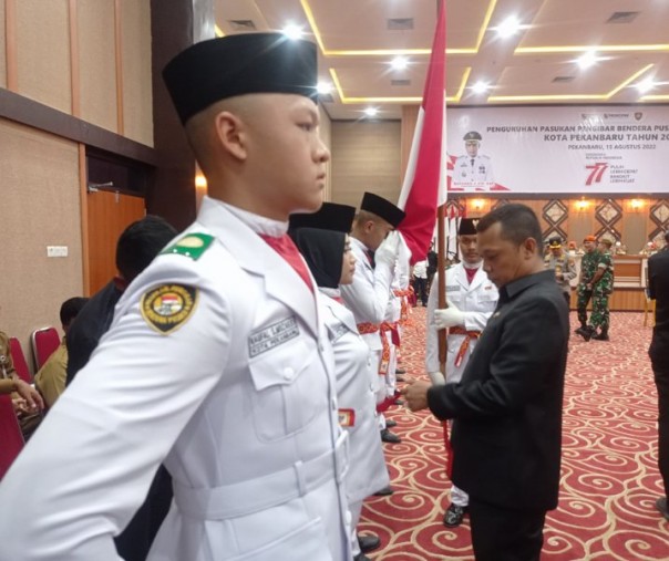 Pj Wali Kota Pekanbaru Muflihun memasangkan ikat di tiap pinggang Paskibra usai pengukuhan di Gedung Utama Kompleks Perkantoran Tenayan Raya, Senin (15/8/2022). Foto: Surya/Riau1.