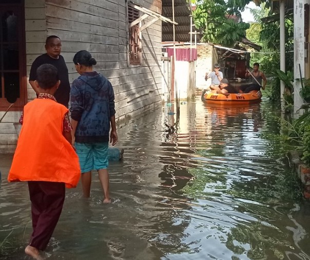 Warga di bantara Sungai Sail (Jalan Dwikora) menggunakan perahu BNPB untuk menuju ke wilayah yang lebih tinggi. Foto: Surya/Riau1.